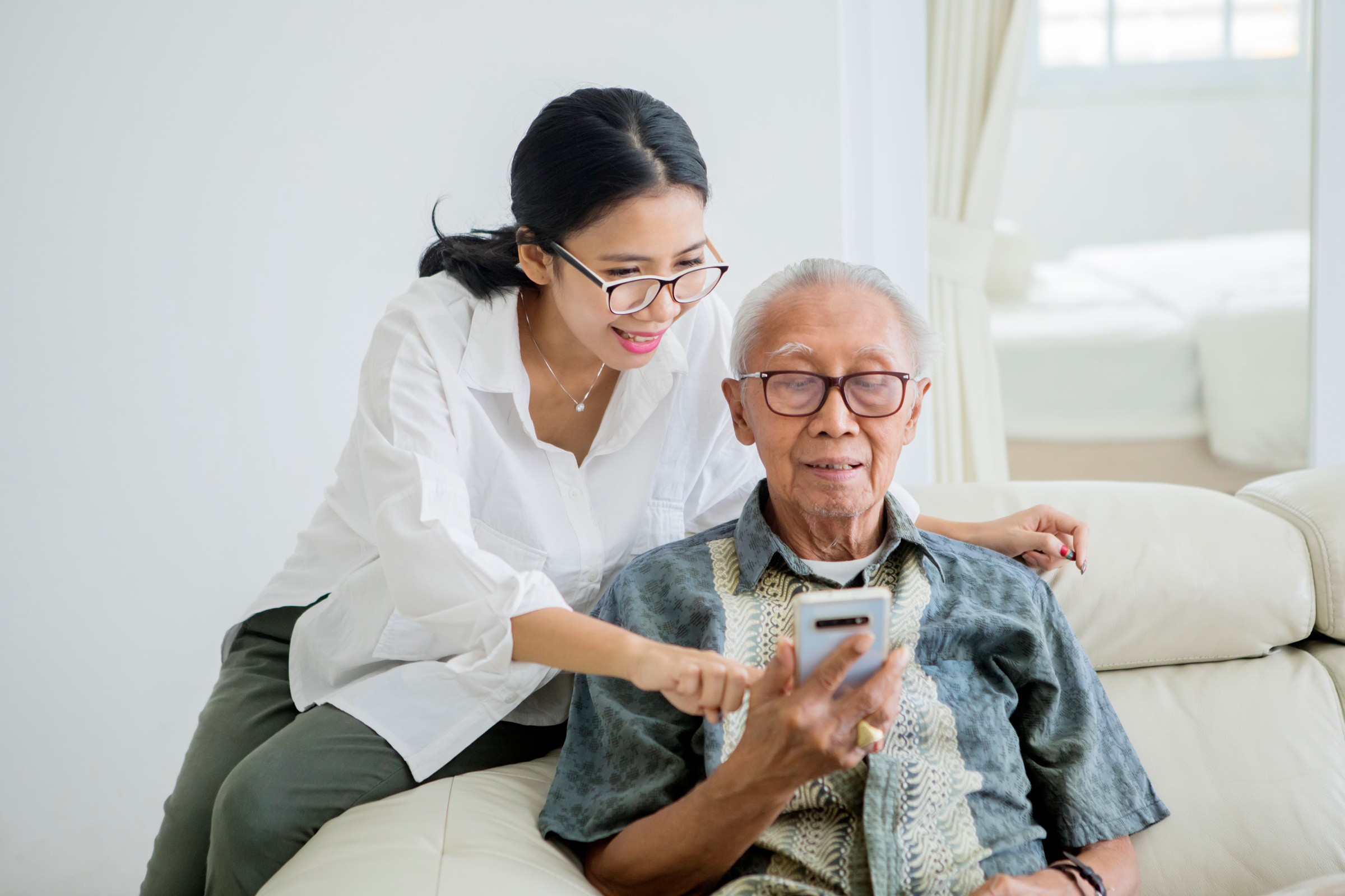 Daughter Teaching and Elderly Father to Use a Phone